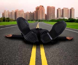 Businessman laying in middle of road exhausted