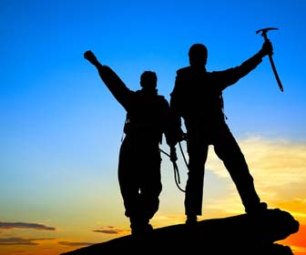 Mountain guide and client at top of peak at sunset picture