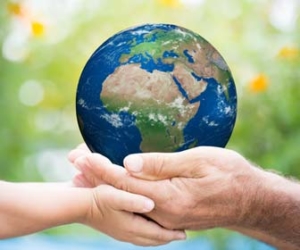 Adult and child hands holding planet earth while outside
