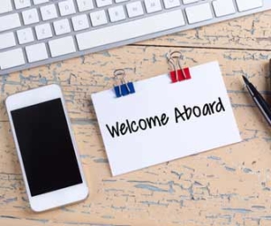 Card saying welcome aboard at desk for employee onboarding