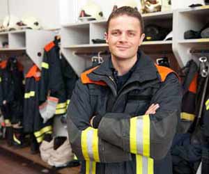 Fireman Posed in Gear Room at Fire Station