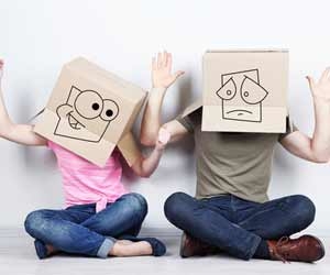 Two people sitting on floor with boxes on heads