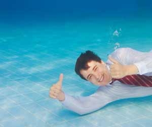 Businessman giving two thumbs up while underwater in swimming pool