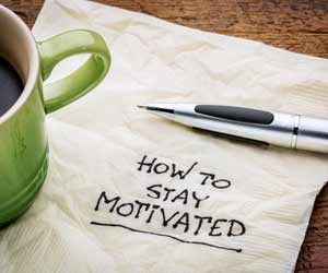 How to Stayed Motivated scrawled on napkin next to coffee