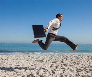 Job hopper jumping along beach in a tie with a briefcase