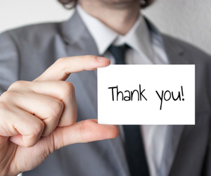 Man in suit holds a thank you card up to show employee appreciation
