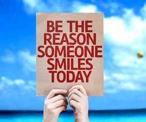 Sign on beach that reads "Be The Reason Someone Smiles Today"