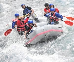 River raft guide with clients while whitewater rafting