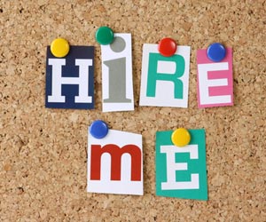 "H.I.R.E. M.E." letters pinned to cork board