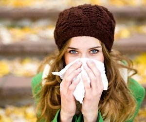 Sick woman blowing her nose while outside
