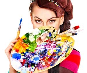 Artist with a messy and colorful paint palette with paintbrushes covering her face