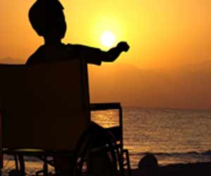 Recreational Therapist Helping Disable Boy Enjoy a Sunset at the Coast