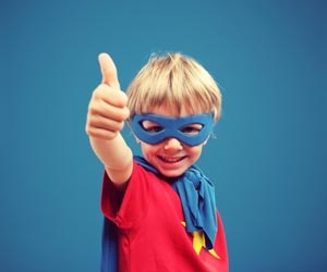Smiling kid dressed as superhero gives a big thumbs up