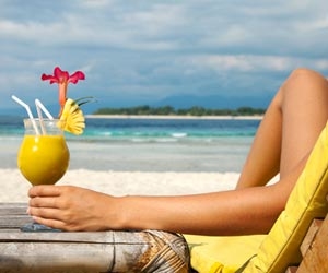 Employee enjoying a drink on the beach while on vacation