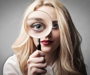 Woman with magnifying glass over eye is searching for jobs