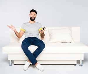 Man with smartphone sitting on white couch