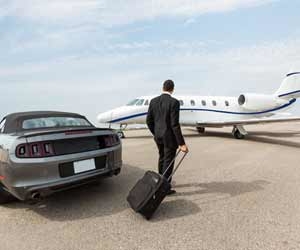 A millionaire businessman exits fancy car to load jet