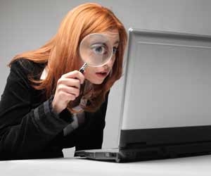 HR professional looking at laptop with a giant eye seen through a magnifying glass