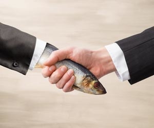 A hand shake featuring a real hand and a dead fish