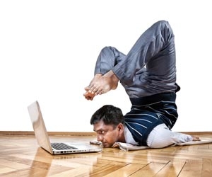 Flexible worker laying on stomach with feet over head while working on laptop