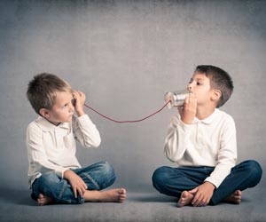 Two children communicating with a tin can on a string