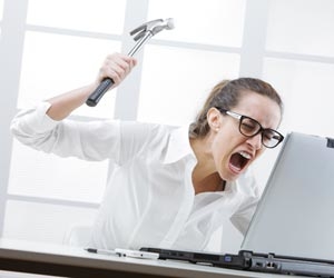 Angry worker about to hit computer with a hammer