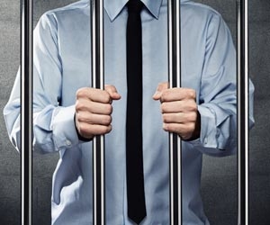 Businessman wearing a tie stands behind bars