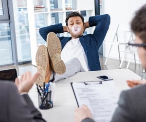 Job candidate with feet on desk and blowing bubble gum during job interview