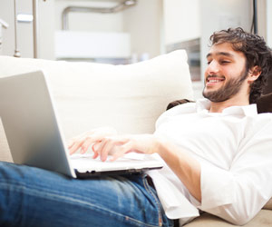 Man on couch typing on laptop