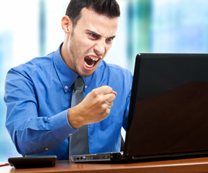 Angry professional yelling and waving fist at laptop computer
