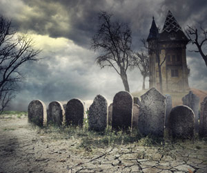 A creepy graveyard in front of a haunted house