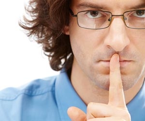 Man in glasses with his finger to his lips