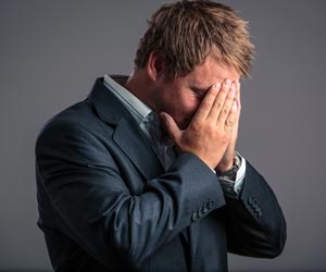 Man in suit holding his head because he is upset